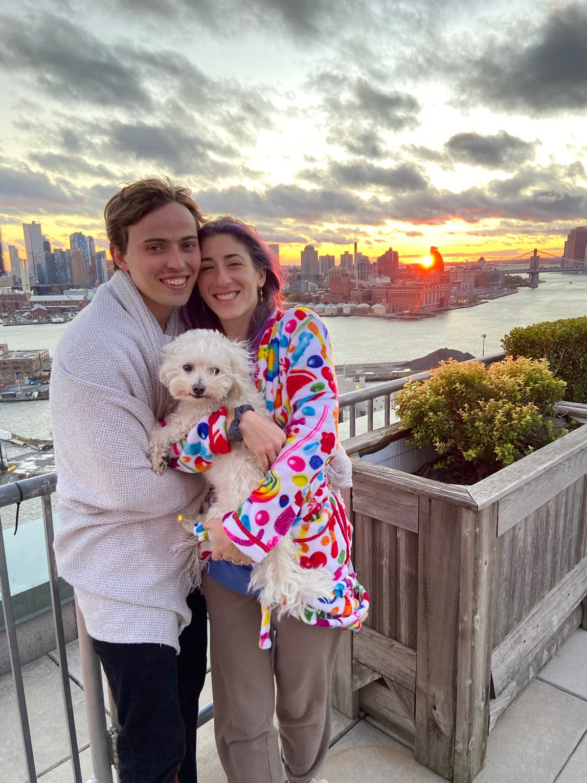 Jen and Luke holding Albus on a rooftop at sunset