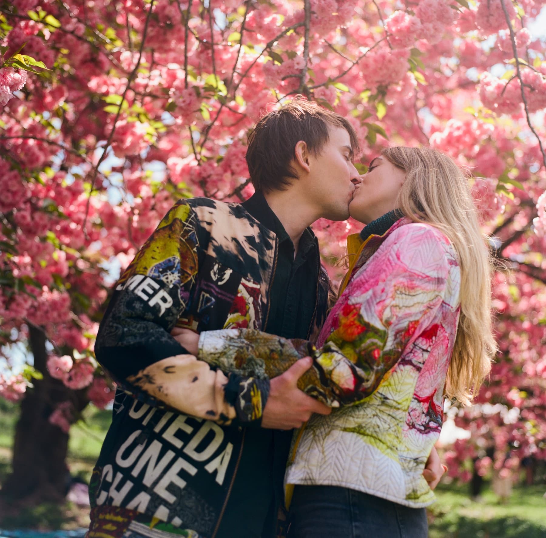 Jen and Luke kissing beneath pink blossoms