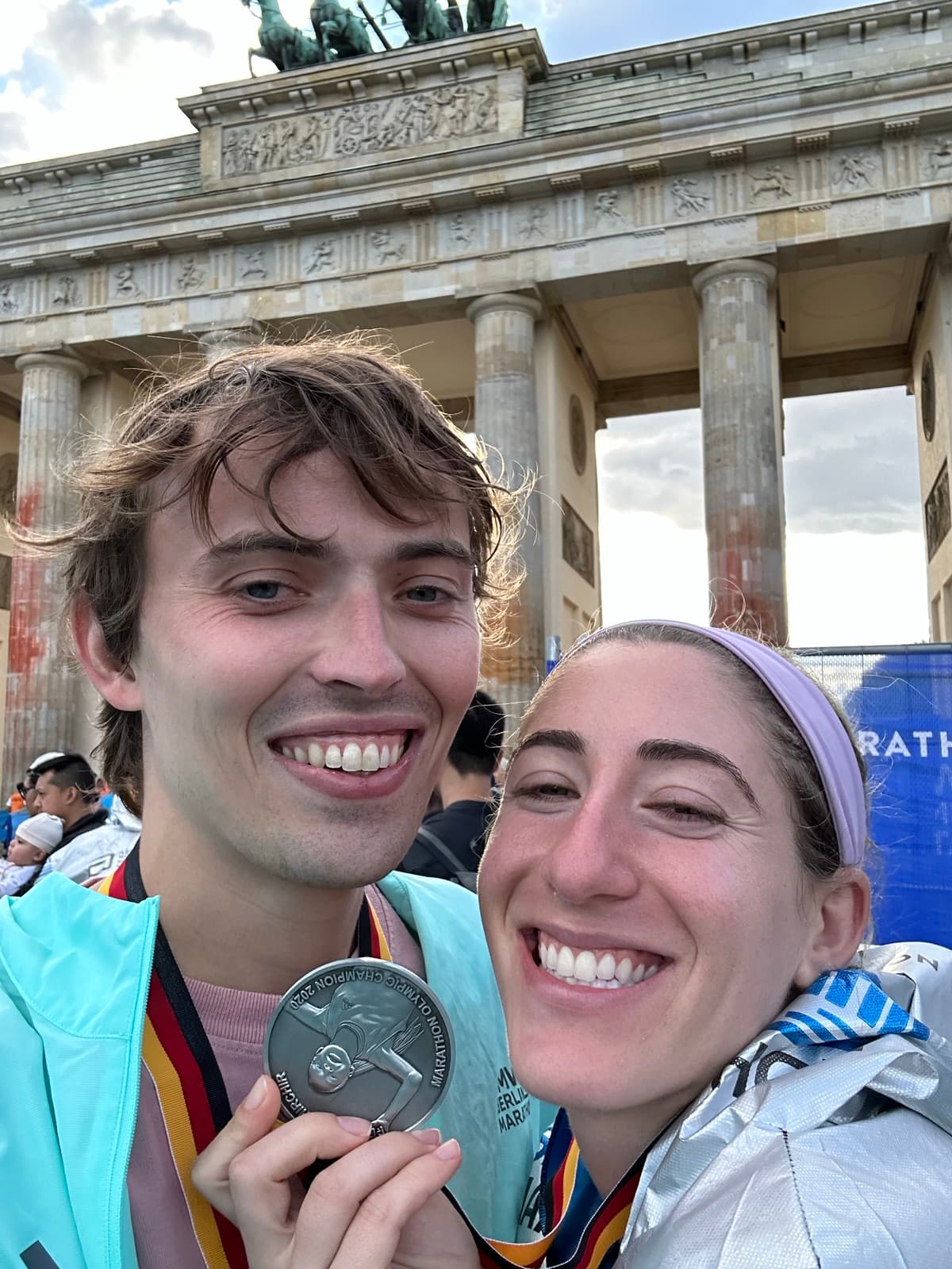 Jen and Luke with a medal in front of the Brandenburg Gate