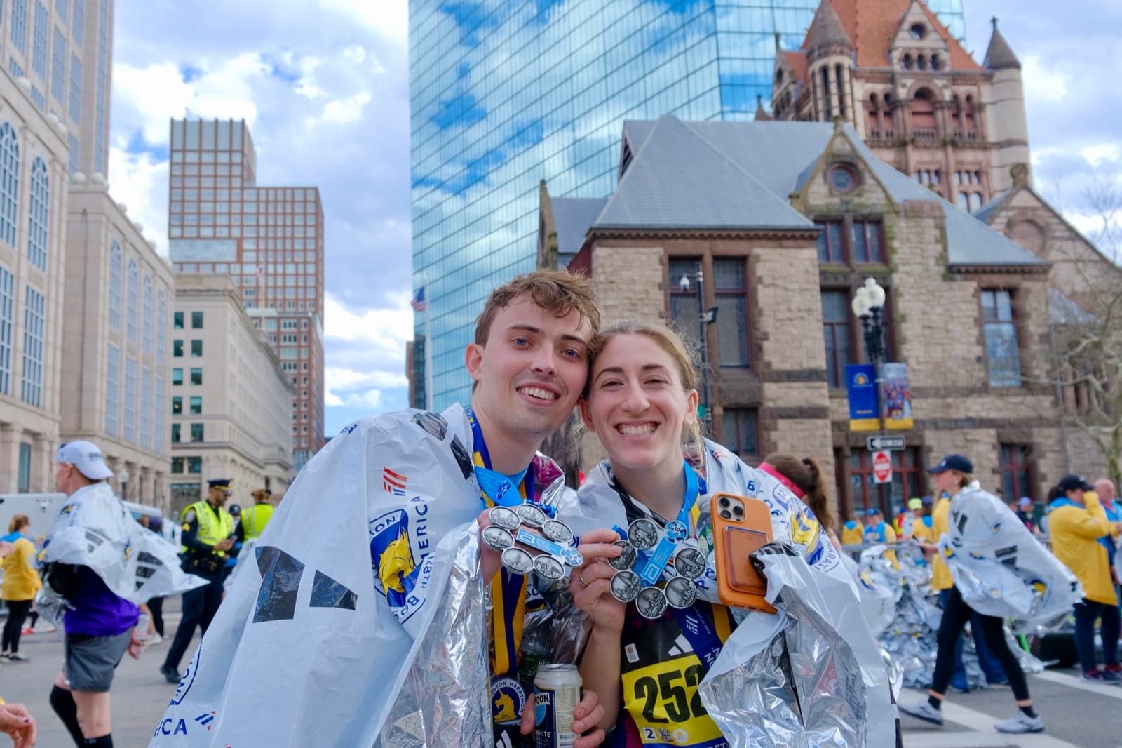 Jen and Luke wrapped in foil blankets with medals at the Boston Marathon finish